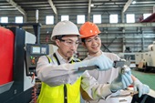 两个工程师穿保护工作服戴着安全帽在工厂做测量