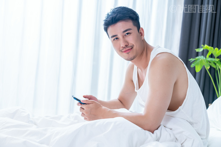 年轻男子在床上玩手机
