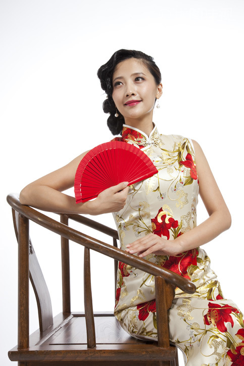 棚拍身穿旗袍的年轻女人拿红色折扇